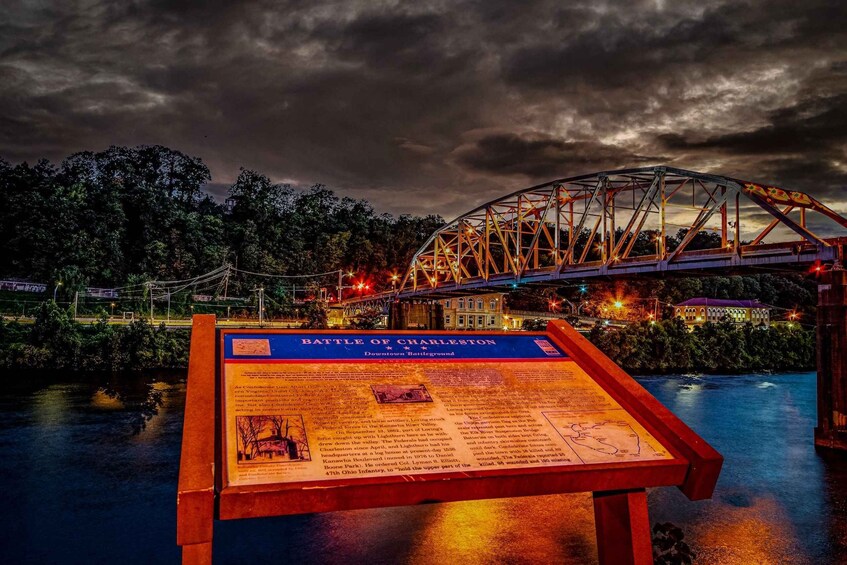 A historical marker titled 'Battle of Charleston' with a bridge in the background. 3