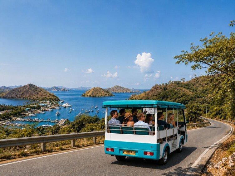 A tour bus driving on a winding road with a coastal landscape and boats in the background. 1