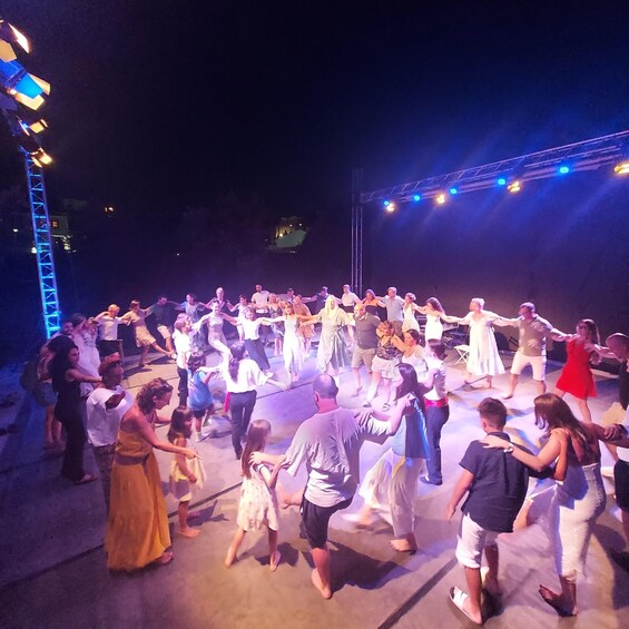 A group of people dancing on an outdoor stage at night. 4