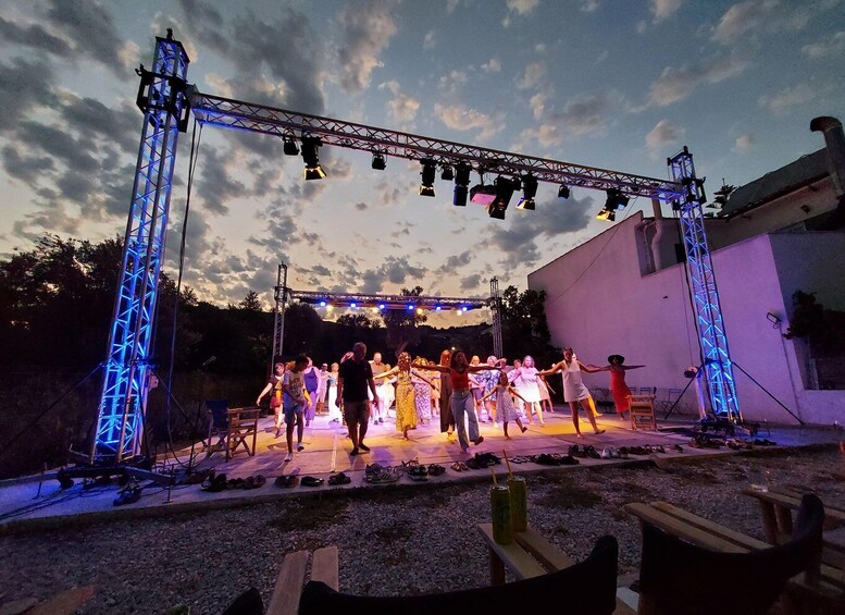 A stage with a group performing under a truss structure at dusk. 1