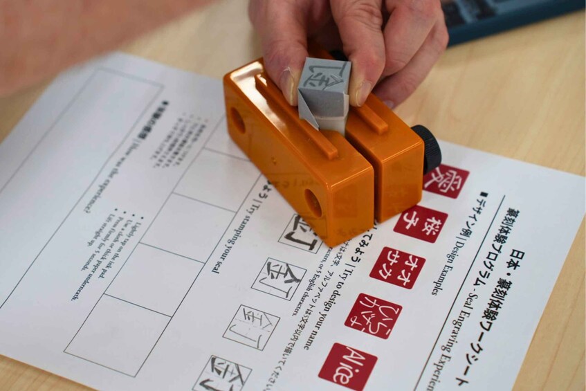A hand using a stamp on a document with Japanese text and symbols. 4