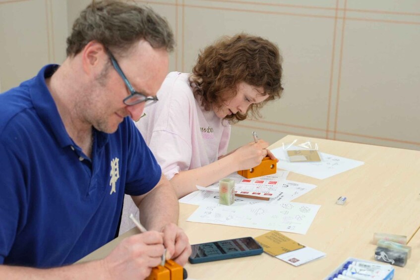 Two people at a table with papers, a calculator, and a small orange object. 5