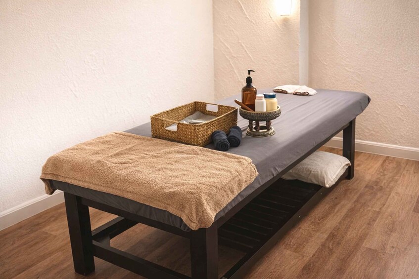 A massage table with a towel, a woven basket, and a tray with bottles and a pump. 3
