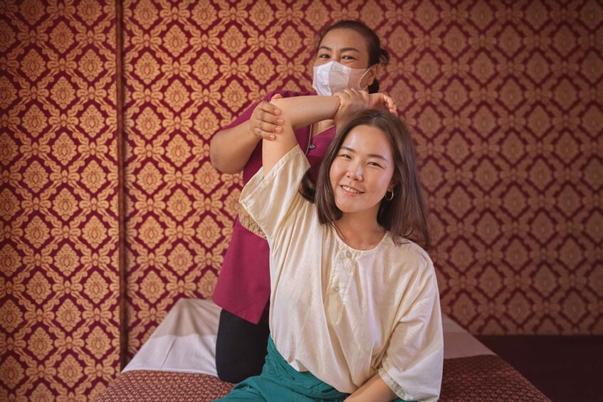 A person receiving a massage with a patterned wall in the background. 2
