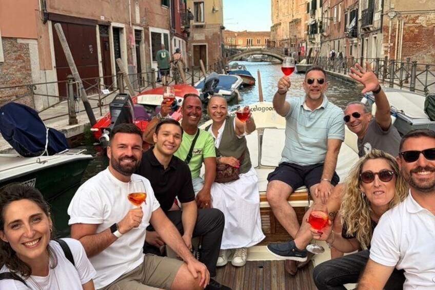 A group of people on a boat in a narrow waterway with buildings on either side. 3