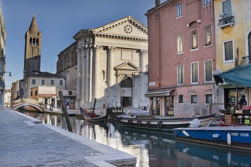 A canal in Venice with gondolas, historic buildings, and a bell tower. 1
