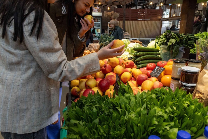 A person selecting fruits at a market stall with various fruits and vegetables on display. 4