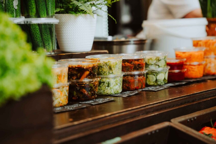 A variety of pickled vegetables in jars on a wooden counter. 5