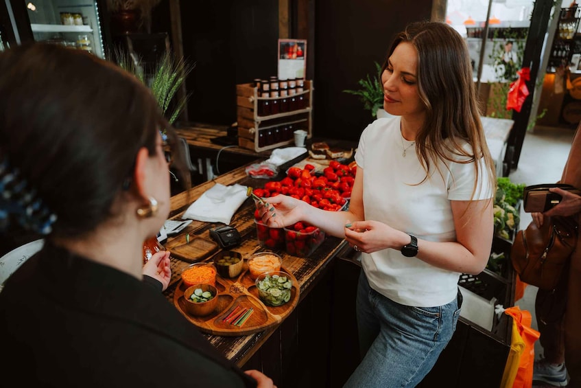 A person serving food at a counter with various dishes and a wine rack in the background. 3