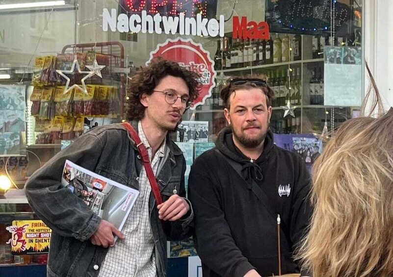 Two men standing in front of a store window with a sign that reads 'Nachtwinkel.' 2