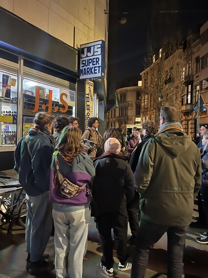 A group of people standing outside a store with a sign that reads 'JJS Super Market.' 1