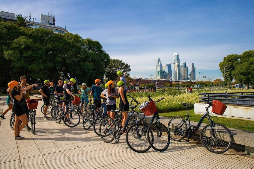 A group of cyclists in a park with a city skyline in the background. 2