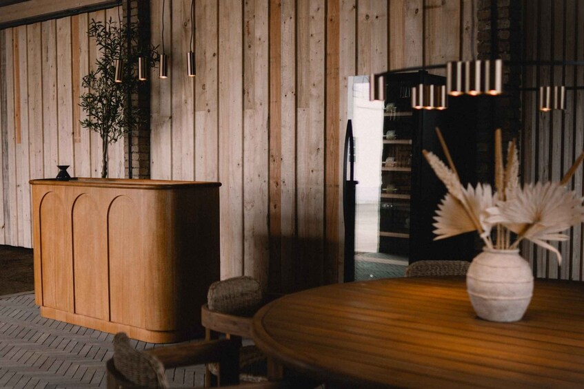 A wooden reception desk, a round table, and a vase with dried plants. 3