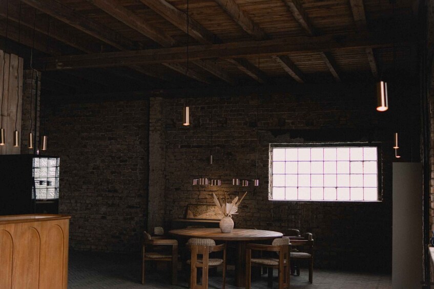 A rustic dining area with a brick wall, wooden ceiling beams, and pendant lighting. 4