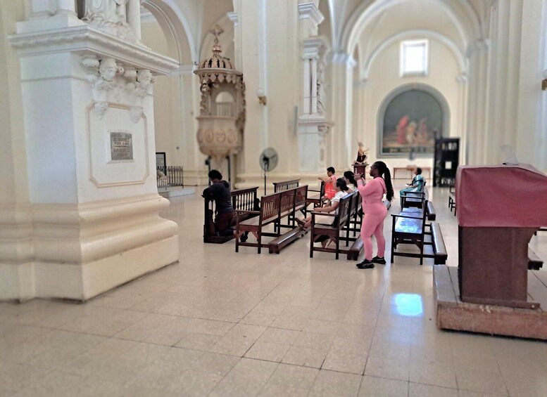 A church interior with pews, a statue, and a chandelier. 4