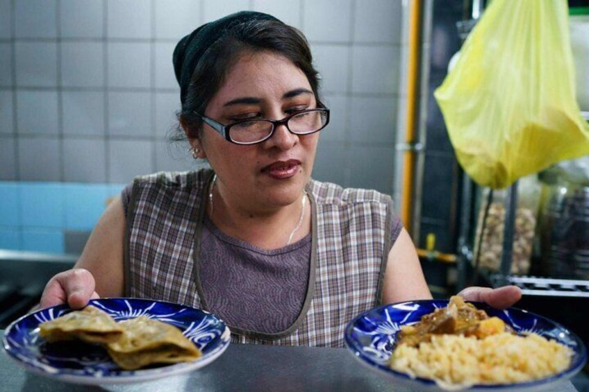 A person holding two plates of food, one with a folded item and the other with a grain dish. 5