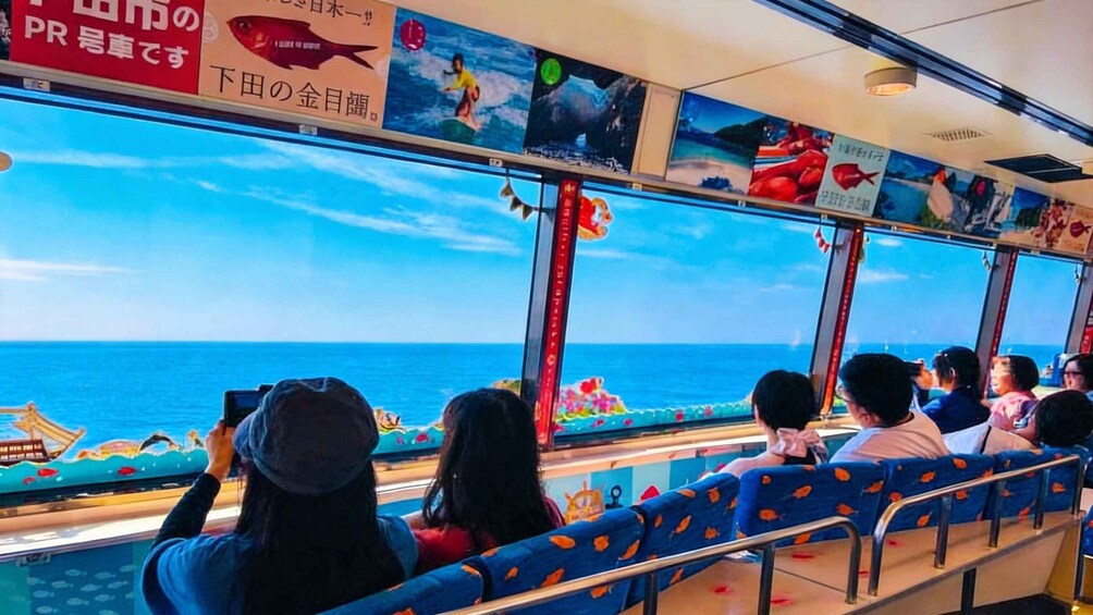 Passengers on a ferry with a view of the ocean through large windows. 1