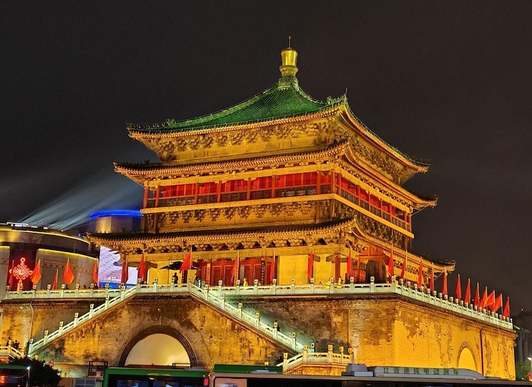 A traditional Chinese building with a green roof and red decorations, illuminated at night. 1