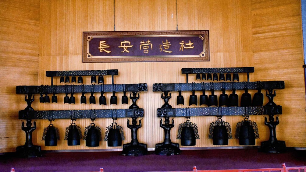 A traditional Chinese gong set mounted on a wooden wall with a sign above. 4