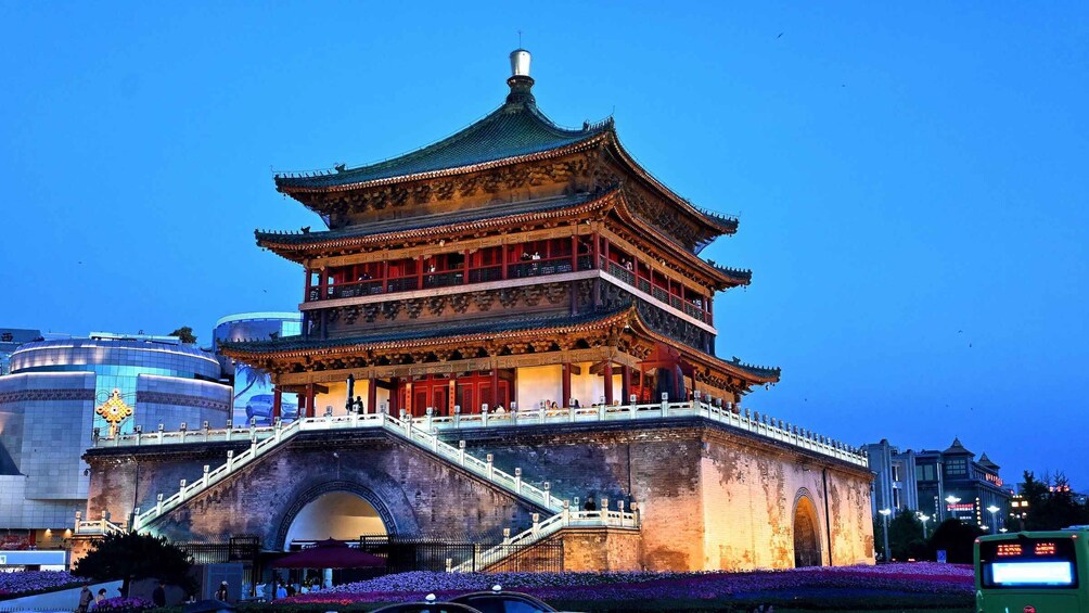 A multi-tiered traditional Chinese pagoda with a green roof, surrounded by modern buildings and a pedestrian bridge. 2