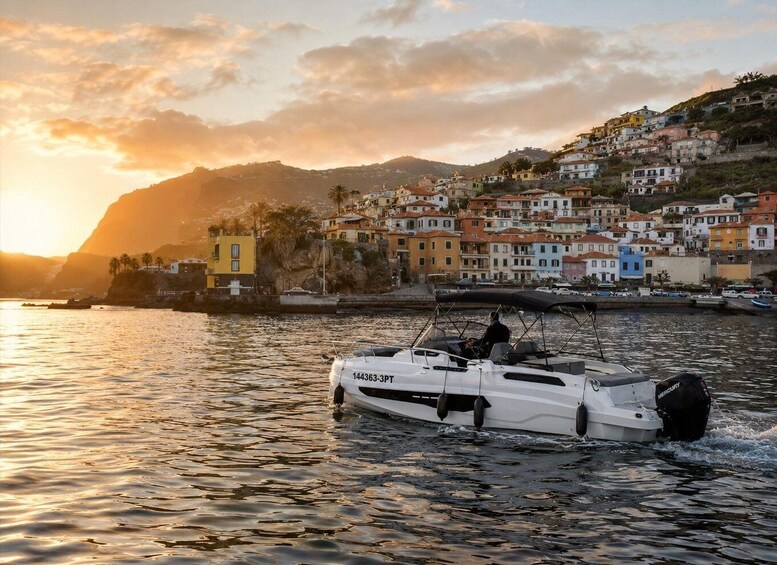 A white boat with the registration number 144363-3PT on a calm body of water, with a colorful coastal town and a mountain in the background. 4