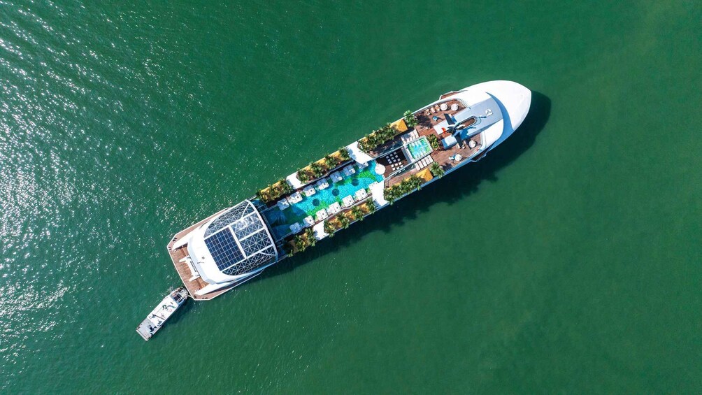 An aerial view of a cruise ship with a swimming pool, sun loungers, and a deck area. 5