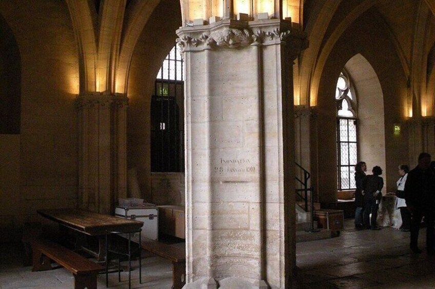 A historical building interior with stone columns, arched ceilings, and a central staircase. 5