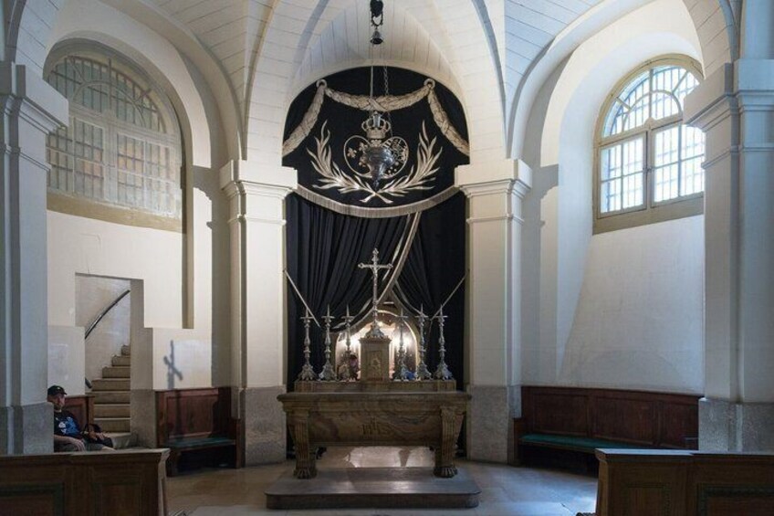 An interior with a central altar, arched ceilings, and a staircase. 3