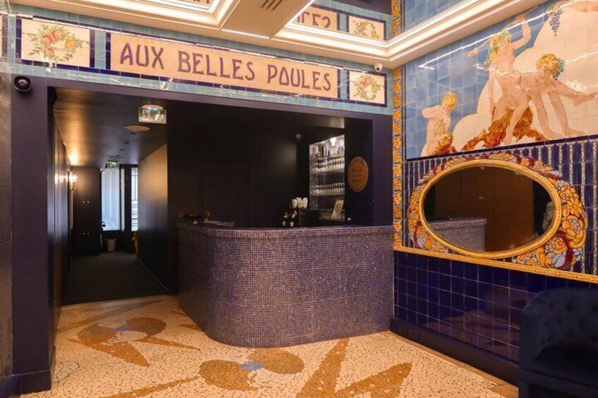 A bathroom with a sign reading 'AUX BELLES POULES,' featuring mosaic tiles and a large mirror. 3