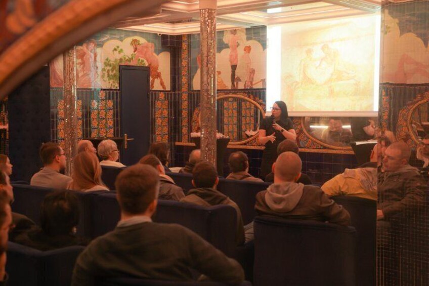 An audience in a theater with ornate decorations and a stage. 4