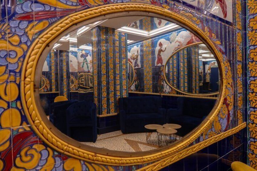 A bathroom with a large mirror, blue walls, and a patterned floor. 5