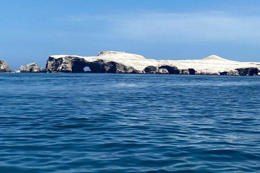A coastal landscape with a rocky outcrop and calm blue waters. 2