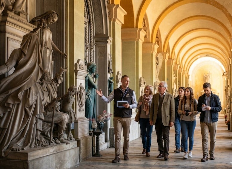 A group of people walking in a corridor with classical statues and arches. 1