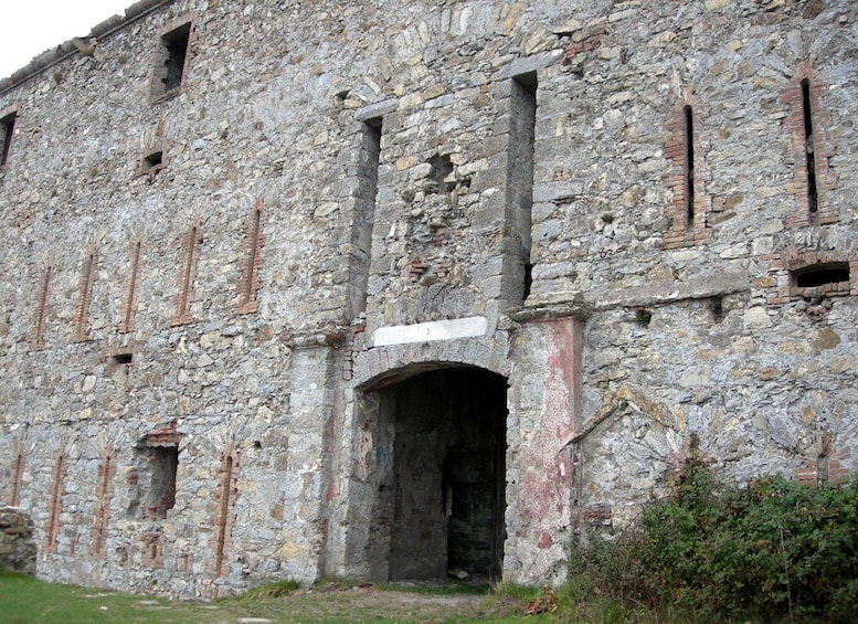 A large, historic stone building with multiple arched doorways and windows. 2