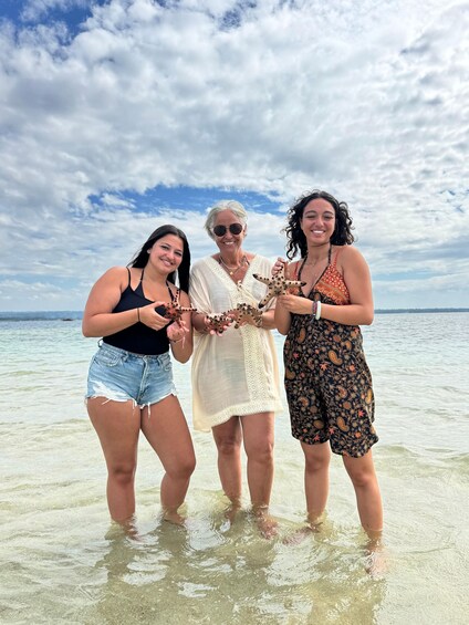 Three people standing in shallow water with a clear sky and distant horizon. 2