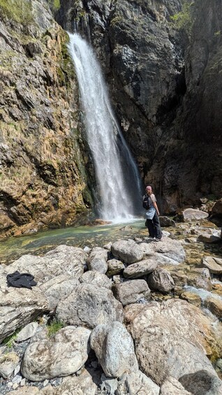 A person standing near a waterfall in a rocky area. 5