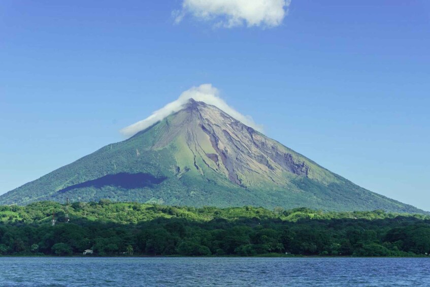 A mountain with a peak covered in greenery and a small cloud at the top. 1