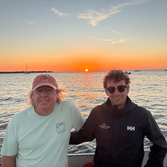 Two people on a boat at sunset with the sun near the horizon. 5