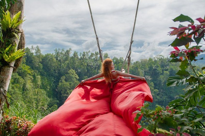 A person sitting on a swing in a lush, green forest. 4