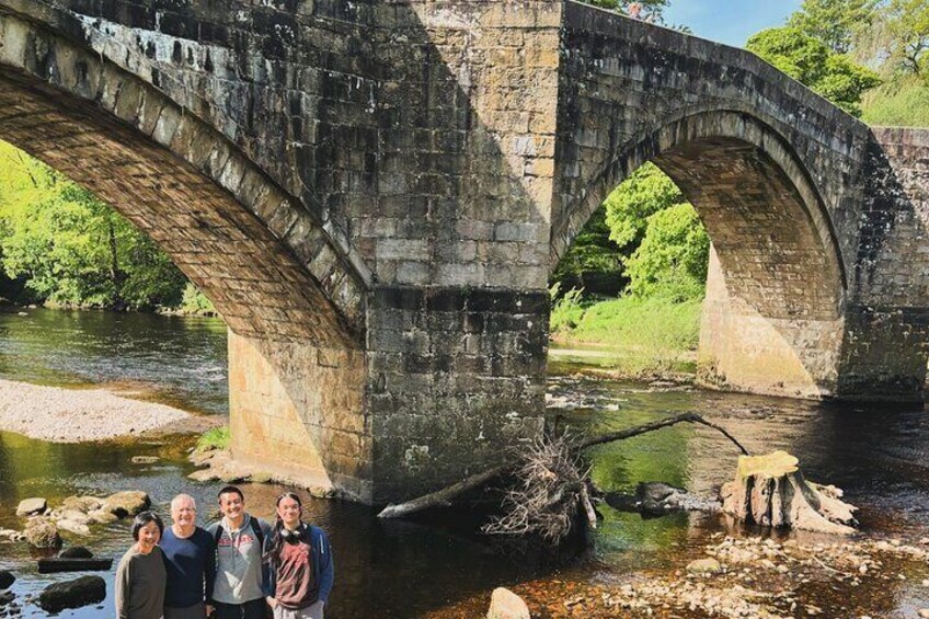 An old stone bridge over a river with greenery around. 5