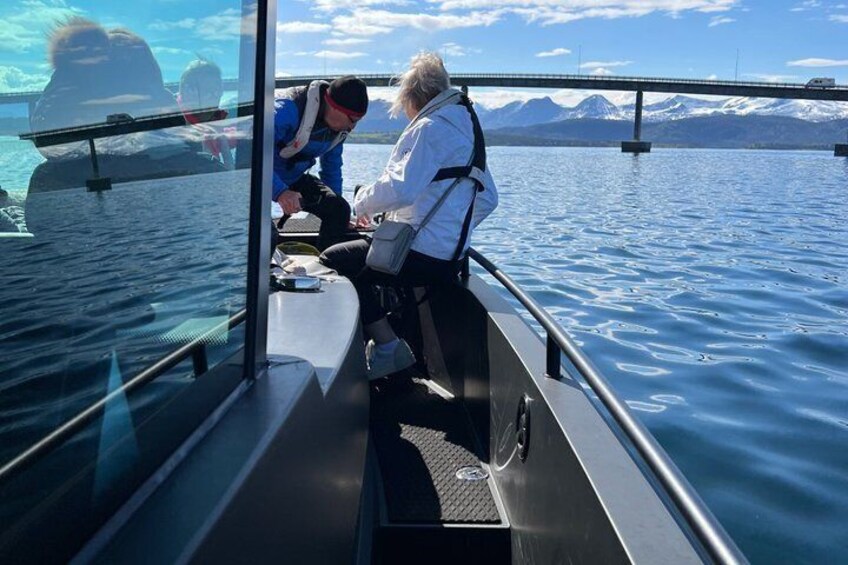 A boat with two people on deck, a clear sky, and mountains in the background. 2