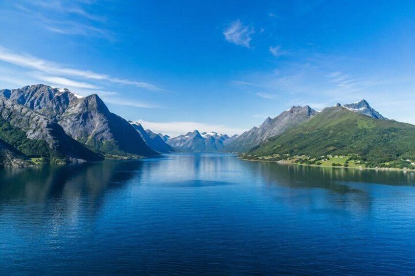 A calm lake surrounded by mountains under a clear sky. 1
