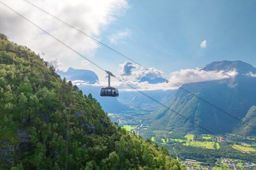 A cable car in a mountainous area with lush greenery and distant valleys. 5