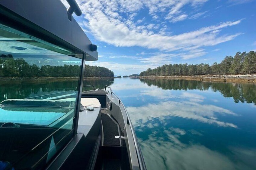 A calm river with a boat, clear sky, and a forested shoreline. 4