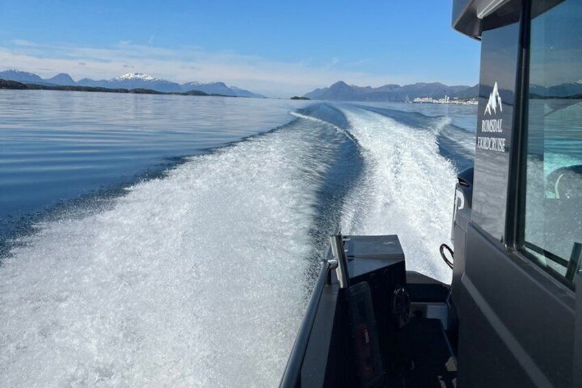 A boat moving through icy waters with mountains in the background. 3