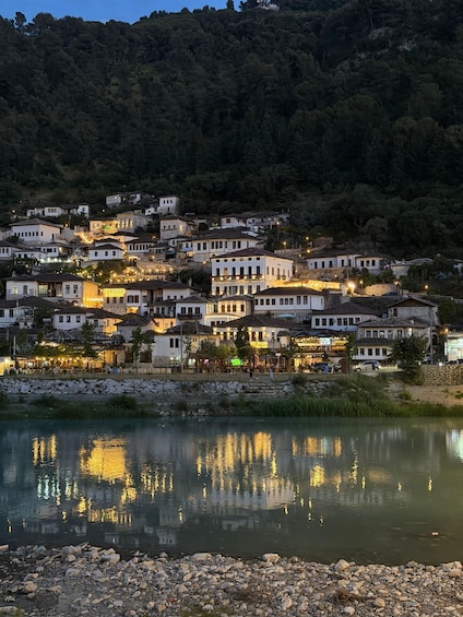A hillside village with buildings reflecting on a calm body of water. 3