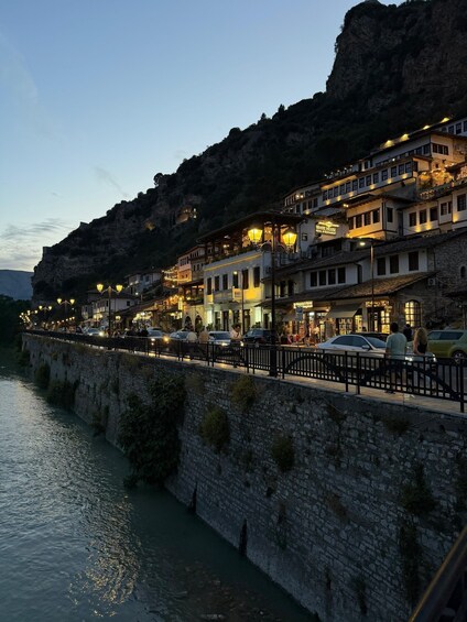 A riverside town with stone buildings, a bridge, and a mountain backdrop. 4