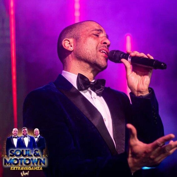 A man in a tuxedo singing into a microphone with a purple-lit background. 5