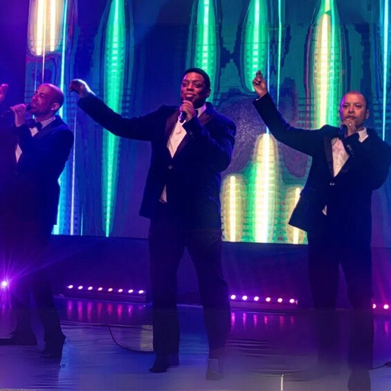 A group of men in suits performing on a stage with a futuristic backdrop. 5