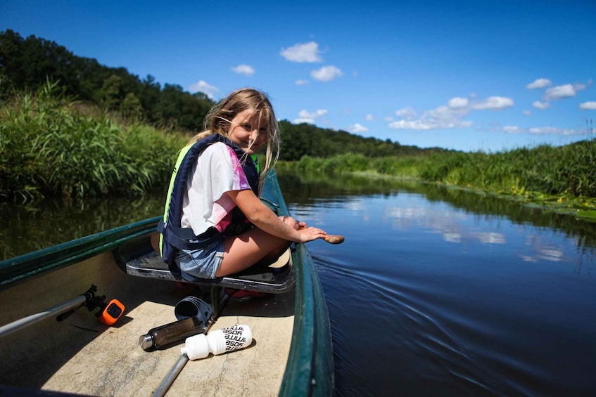 A person in a canoe on a calm river surrounded by greenery. 3